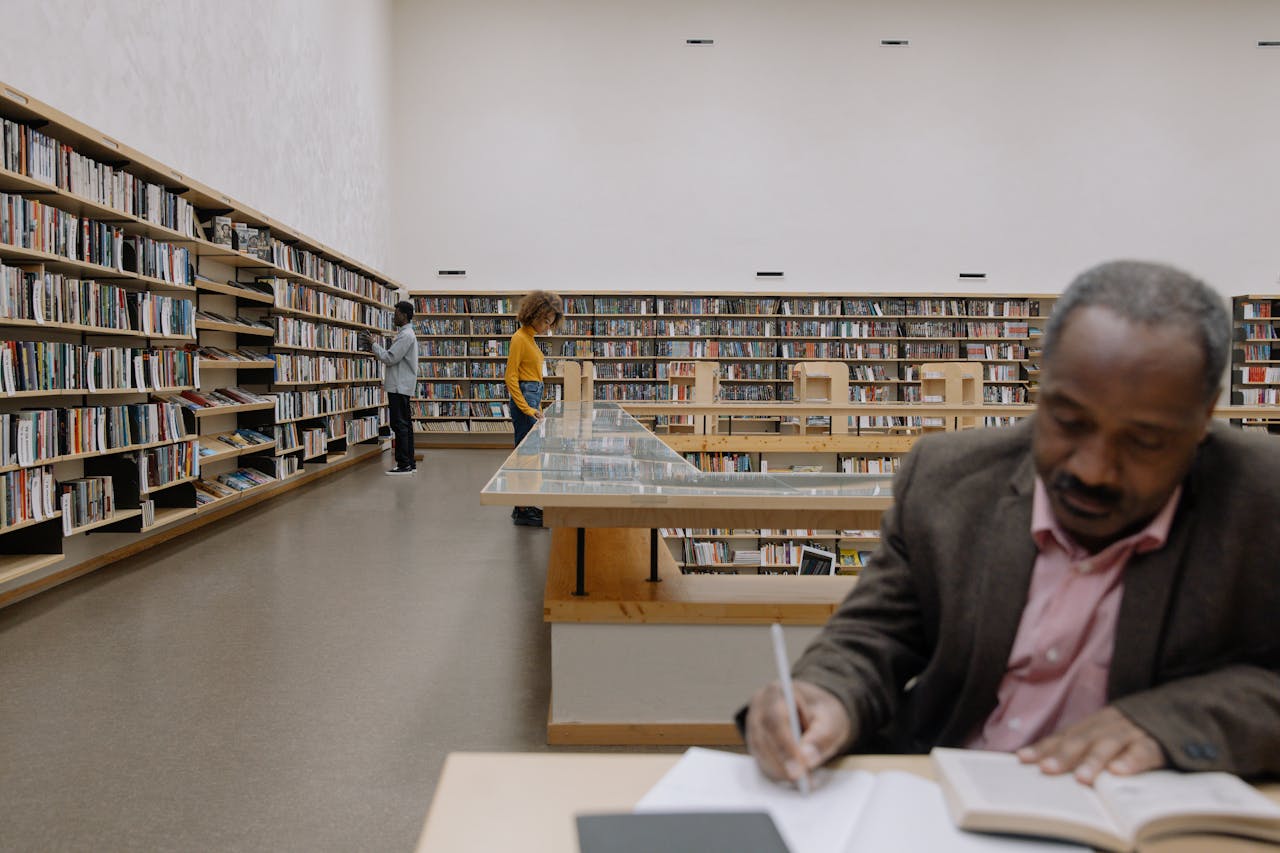 A diverse group of adults reading and studying in a spacious, modern library.