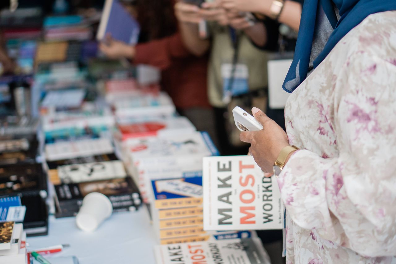 hero-about Close-up of various books on display at a book fair with attendees browsing.