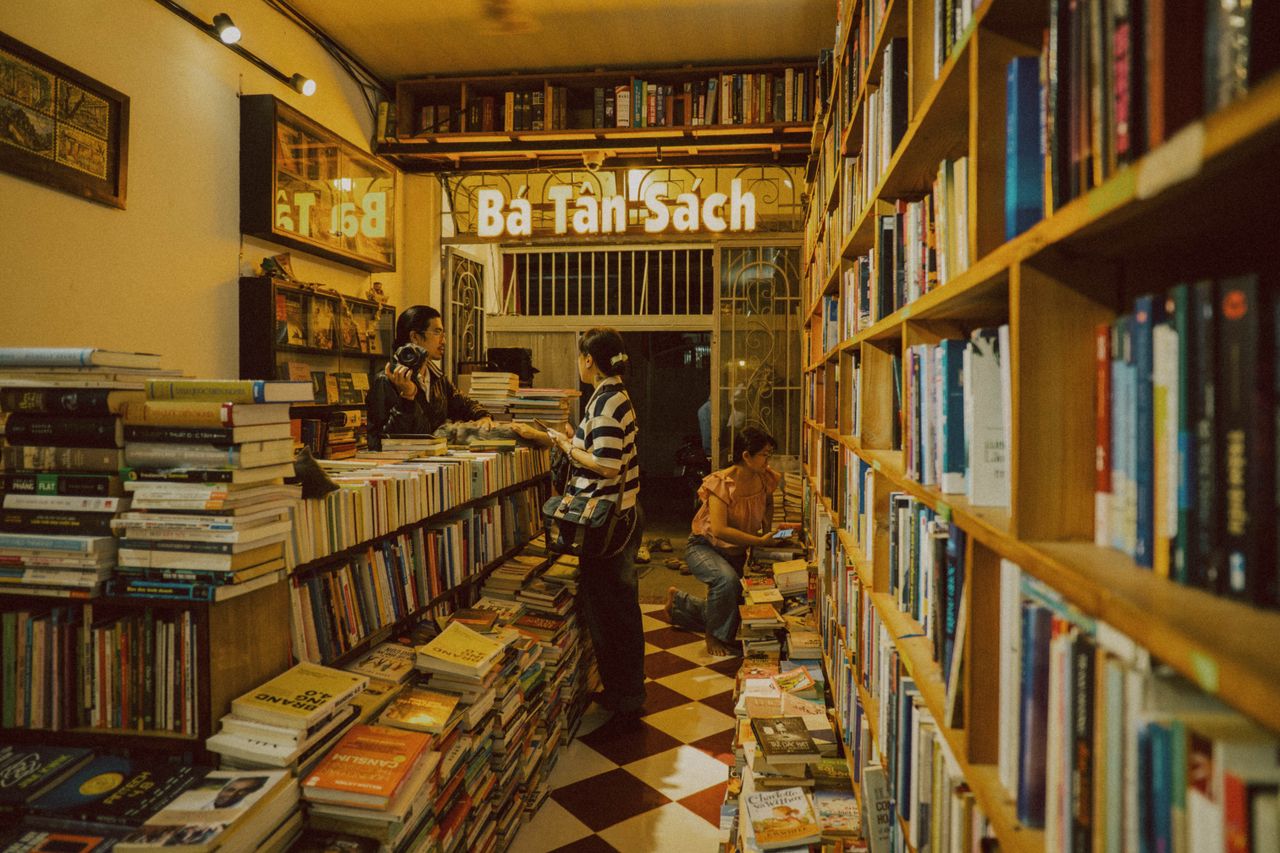 about-02 Warm, inviting bookstore with customers browsing books in a quaint indoor setting.
