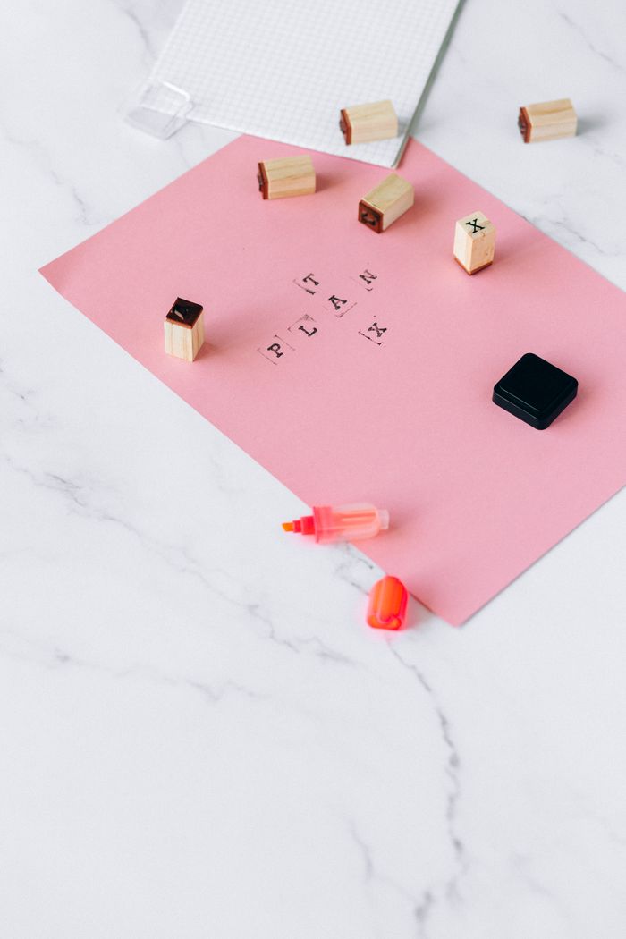 The Art of Drawing Readers In: Your attractive post title goes here A flat lay of pink paper with planning stamps on a marble surface, symbolizing creativity and organization.