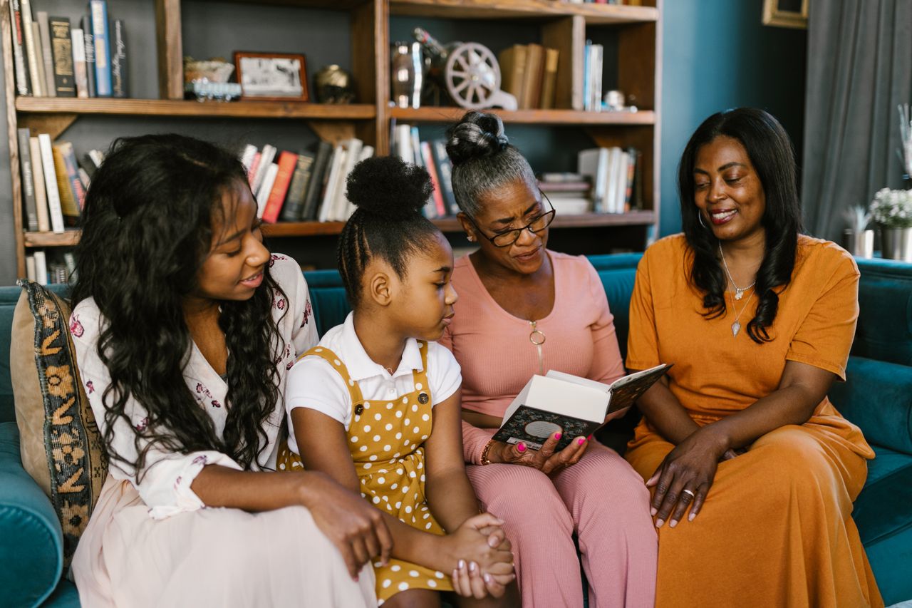 A multigenerational family enjoys reading at home, sharing smiles and togetherness.